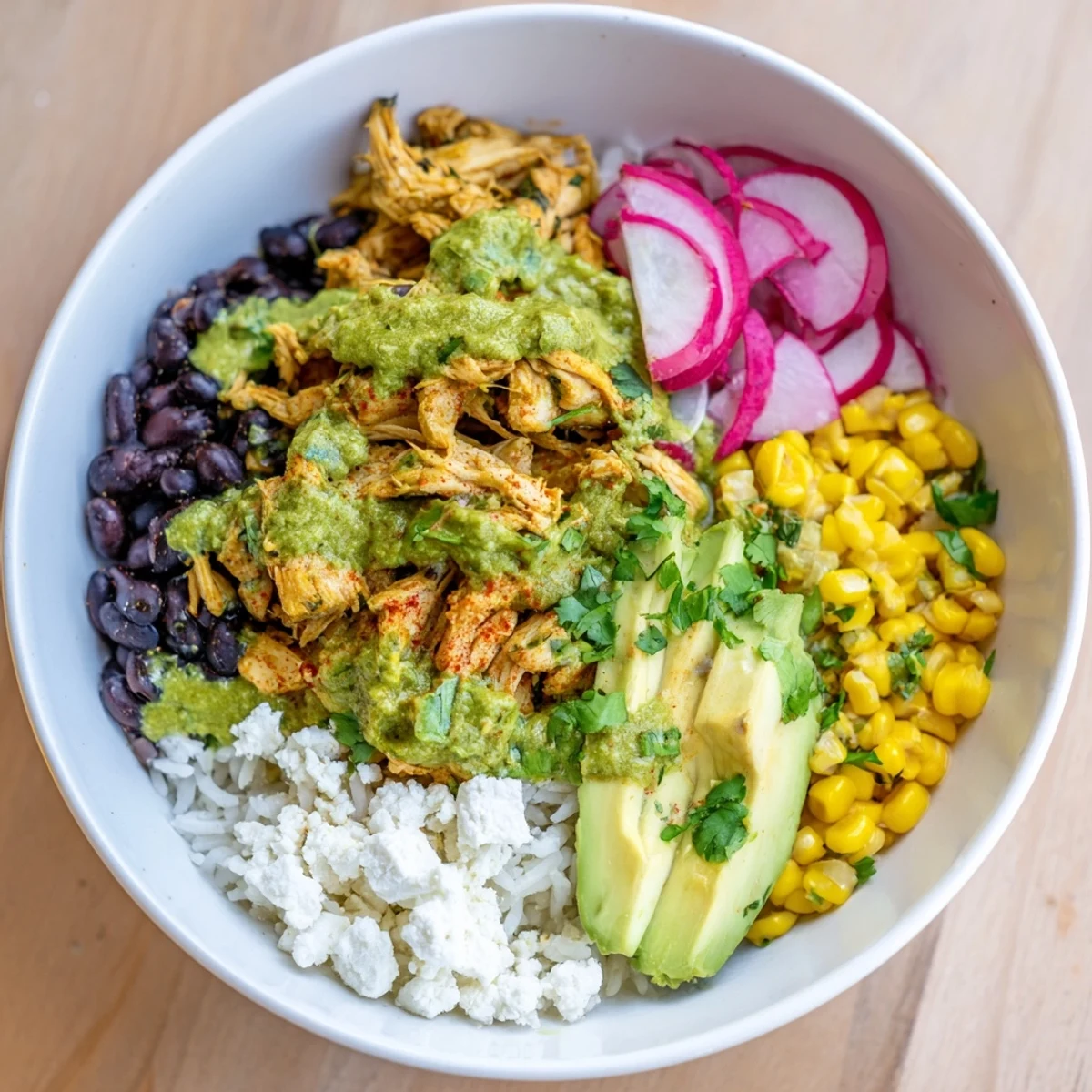 A colorful green enchiladas rice bowl topped with avocado, ready to be eaten.