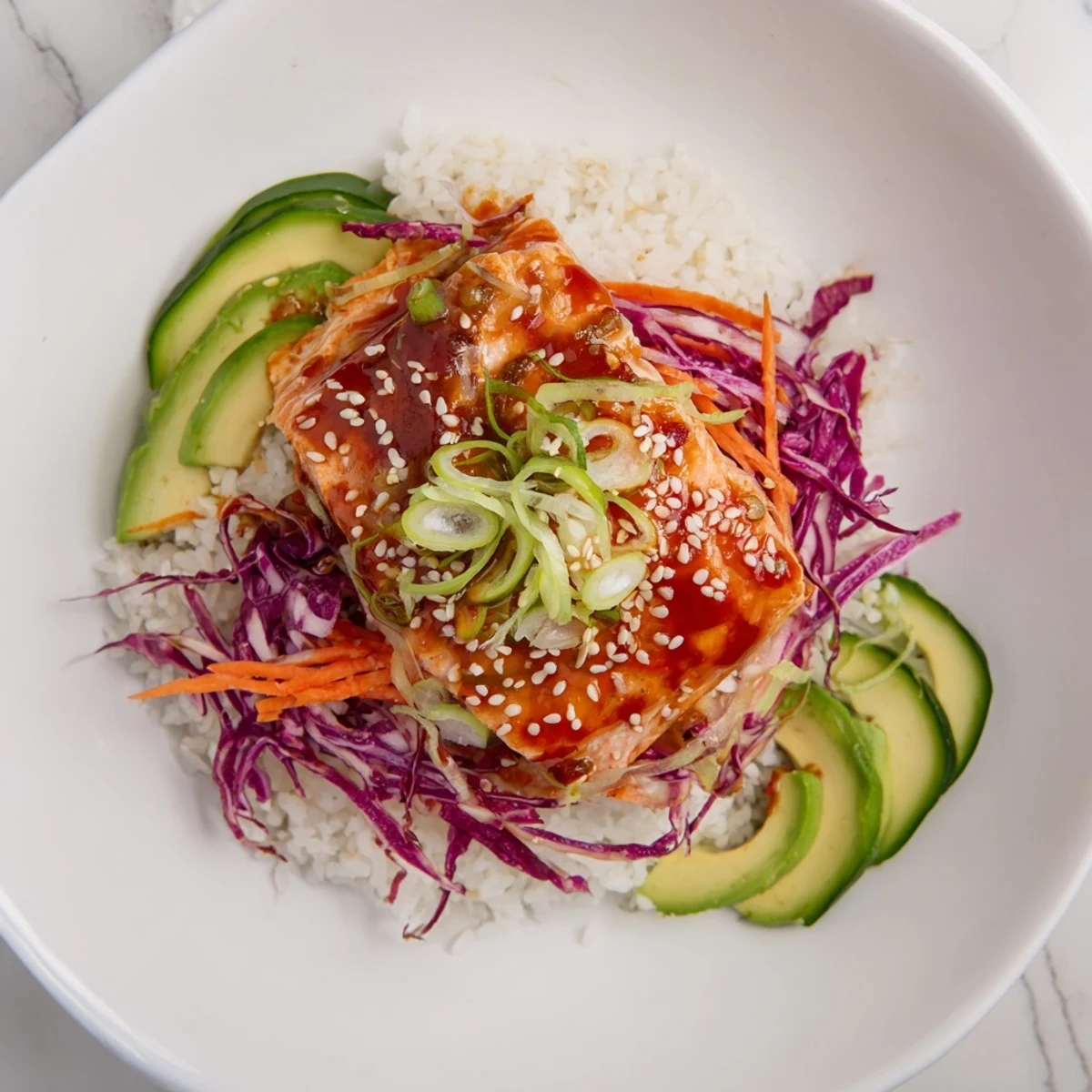 The beautifully arranged Sweet Chili Salmon Rice Bowl features sesame seeds and vibrant garnishes for a delicious dish.
