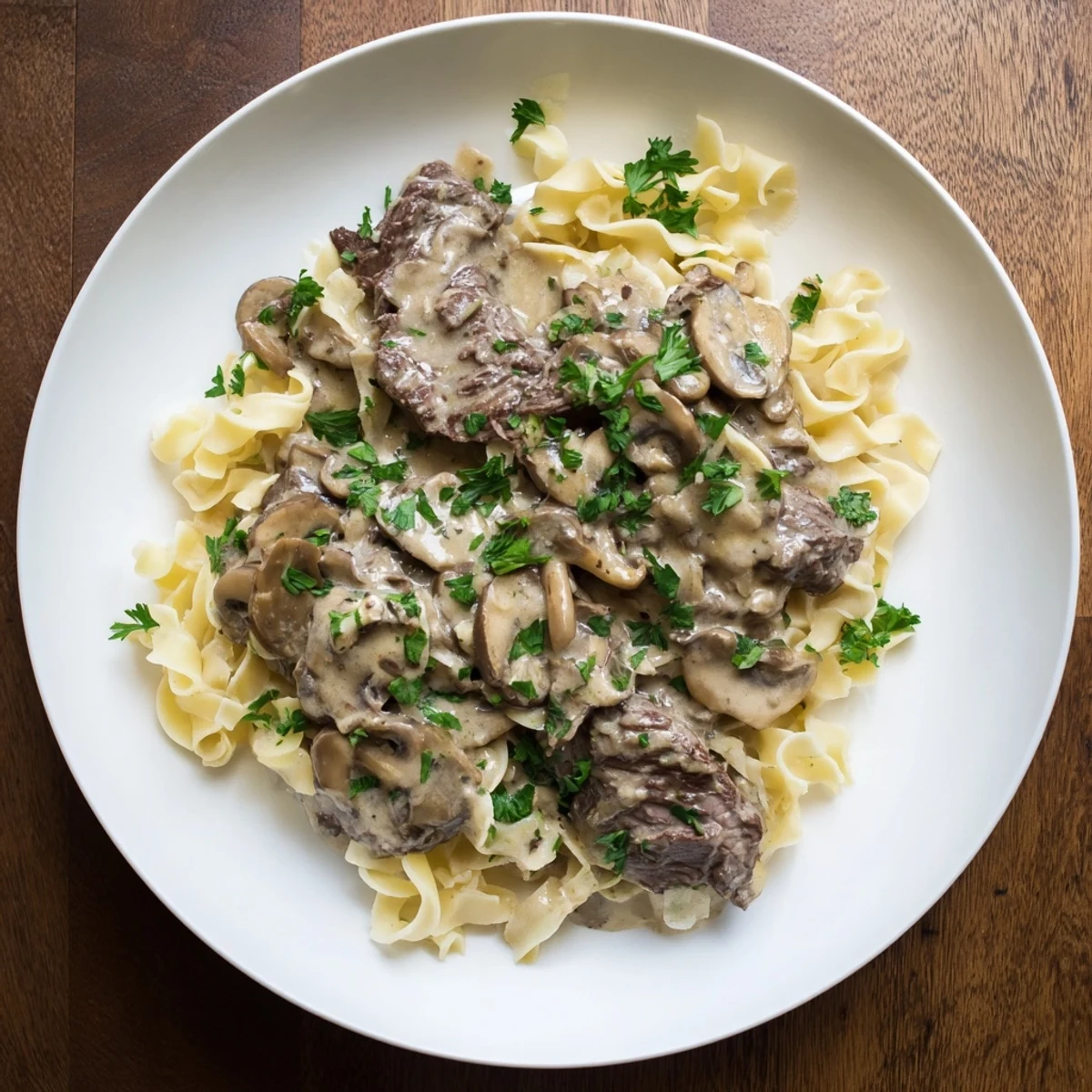 Picture this: a generous serving of Creamy Mushroom Beef Stroganoff, garnished with parsley, on a white plate.