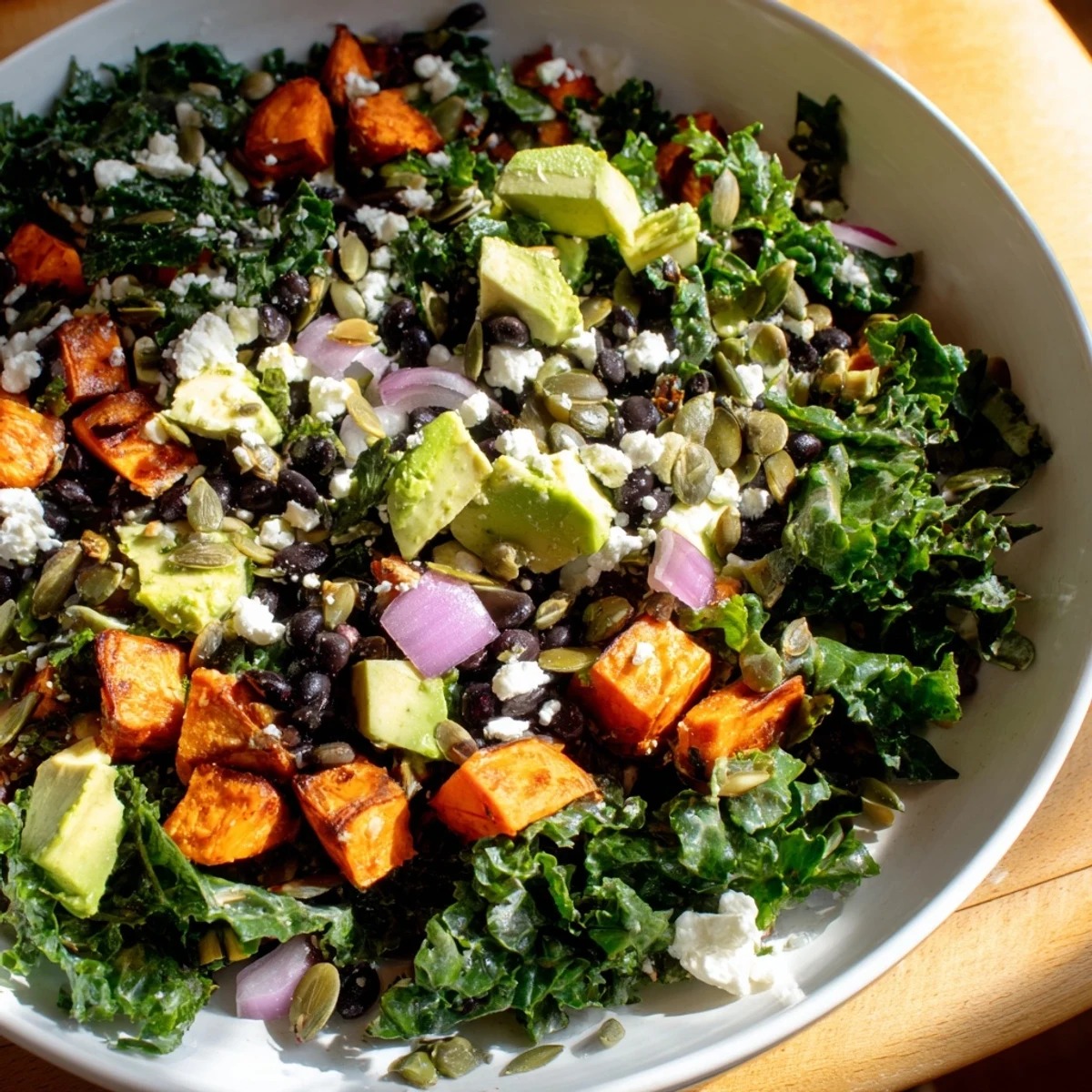 A colorful, fresh Massaged Kale Salad with black beans, sweet potato, and creamy avocado, ready to serve.