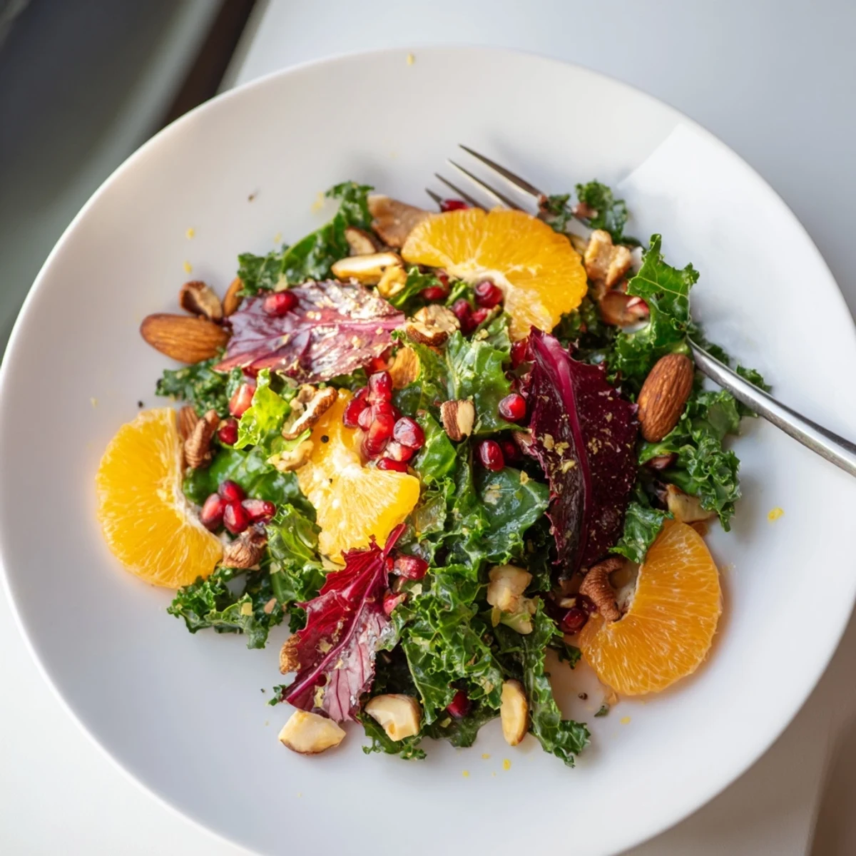 Vibrant Winter Greens Salad boasts citrus segments, ruby pomegranate seeds, with toasted nuts visible on top.