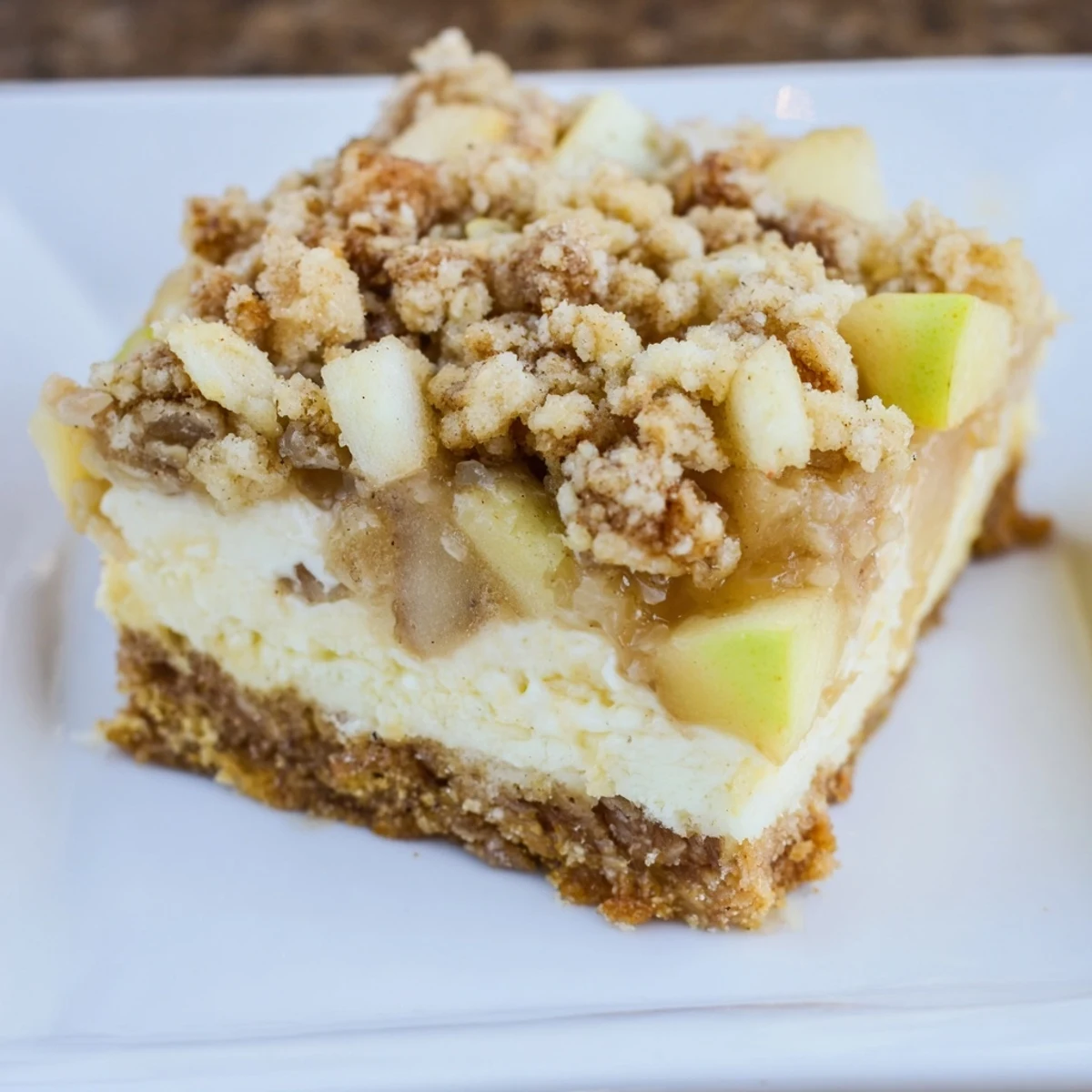 Golden-brown Apple Crisp Cheesecake Bars, a layered dessert with a spiced apple center waiting to be enjoyed.
