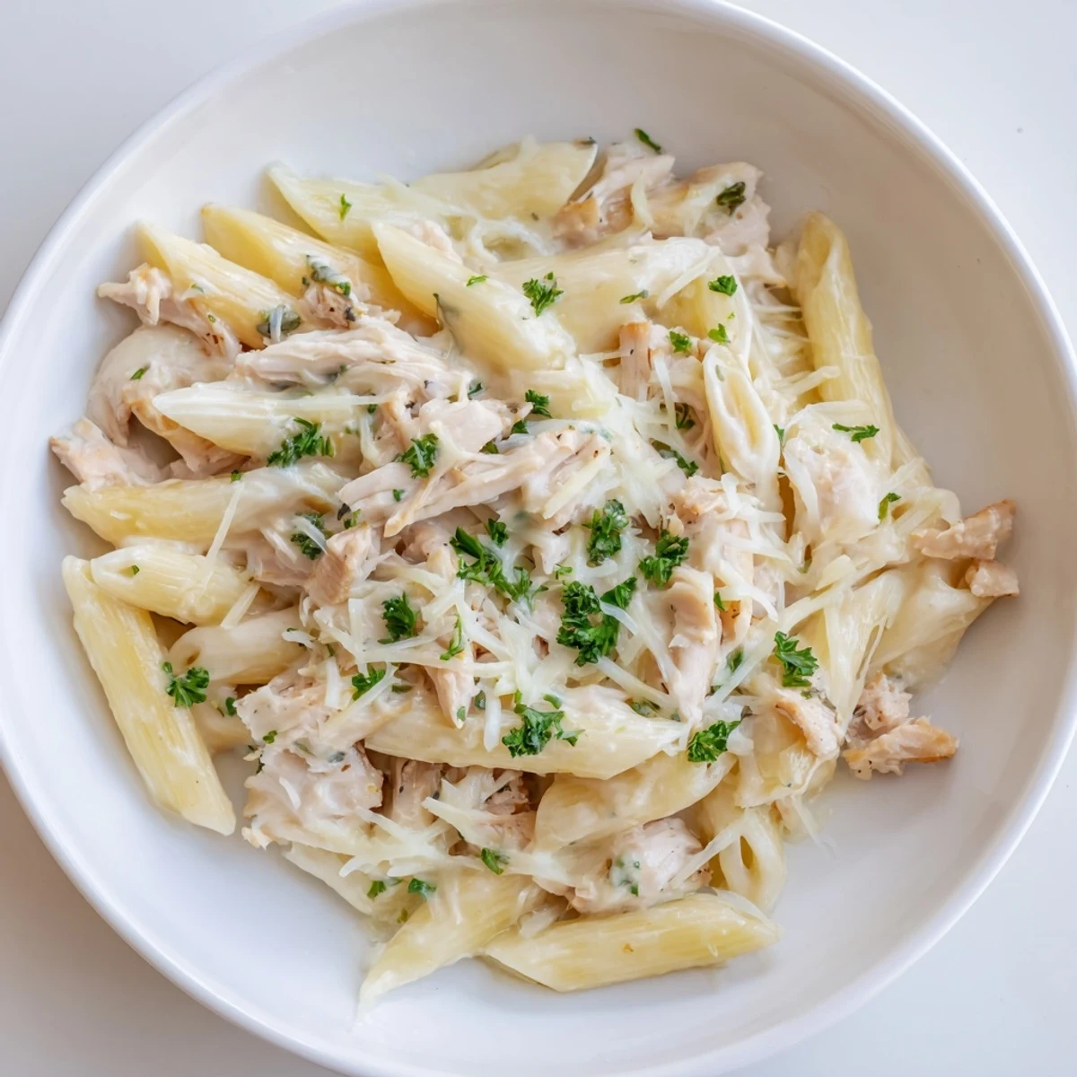 Tini's Creamy Chicken Pasta: a comforting bowl of pasta with creamy sauce, fresh parsley, and shredded juicy chicken.