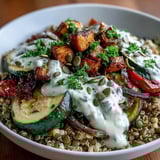 A hearty bowl of fluffy quinoa and green lentils is generously topped with caramelized vegetables and fresh parsley.