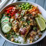 Spicy creamy peanut sauce drizzled over Thai Peanut Chicken Bowl with fresh lime and cilantro.