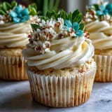 Vanilla cupcakes with smooth buttercream frosting, decorated with vibrant edible flowers for a seasonal treat.  