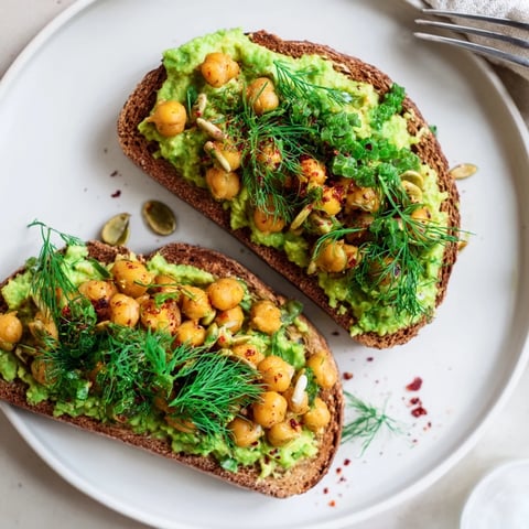 Creamy avocado toast with chickpeas and herbs, a colorful breakfast or light lunch idea.