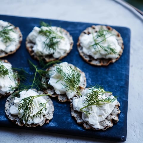 Crisp grey crackers topped with creamy goat cheese, showcasing The Stormy Sea appetizer's sea foam.