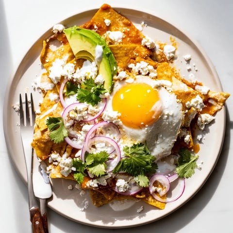 Crispy tortilla chips coated in vibrant salsa verde, topped with a runny egg, queso fresco, and fresh avocado slices for this classic Mexican Chilaquiles breakfast.