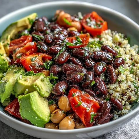 Bright cherry tomatoes, diced avocado, and a medley of beans fill this Three-Bean Power Bowl, served on a bed of fluffy quinoa and drizzled with zesty lemon dressing.