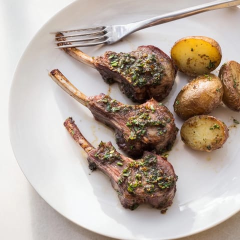 Sizzling herbed lamb chops with roasted potatoes, featuring tender meat and perfectly seasoned, golden potatoes.