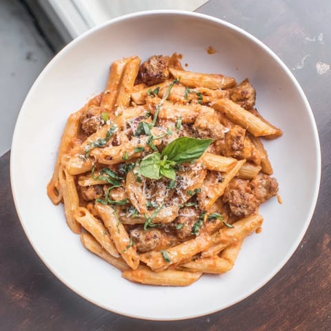 This Creamy Tomato and Sausage Pasta shows al dente penne coated in a luscious, creamy tomato sauce.