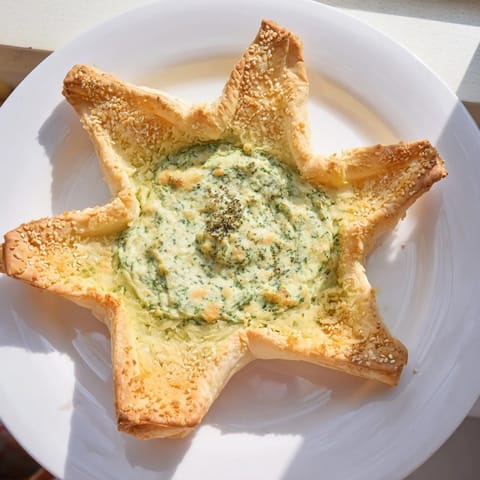 Golden, flaky pastry surrounds creamy green star-shaped pesto dip, perfect for a party appetizer.