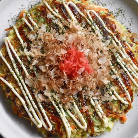 A close-up of steaming, delicious Okonomiyaki pancakes with bonito flakes for a lovely texture.