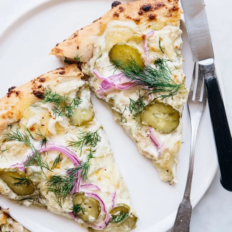 Slice of Pickle Pizza featuring crunchy dill pickles and rich crème fraîche, a unique delight.  