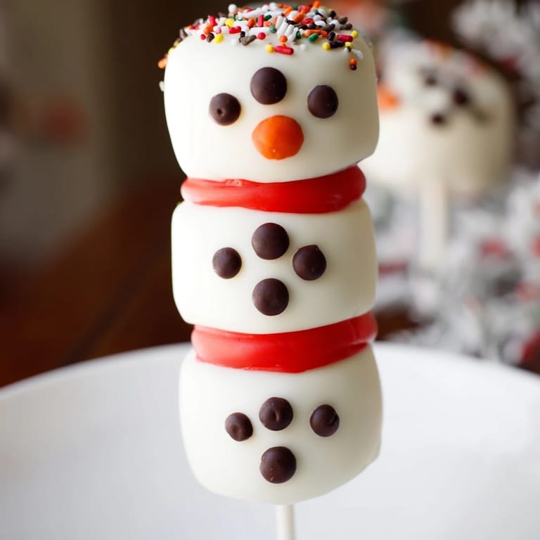 Homemade Express Snowman Marshmallow Pops: cute marshmallow snowmen with candy scarves, perfect winter dessert.