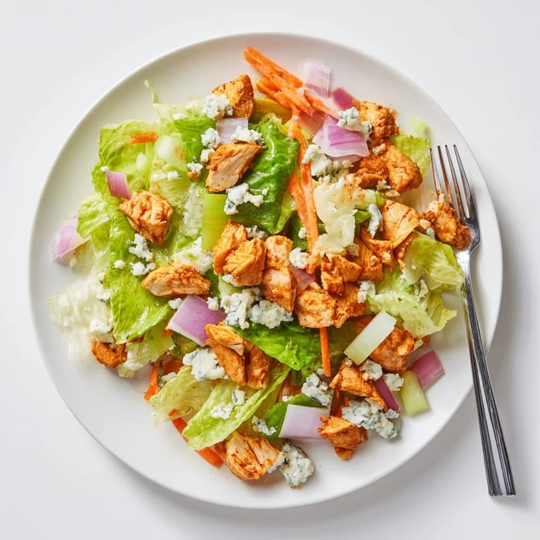 Freshly chopped romaine and juicy Buffalo Chicken Chopped Salad tossed with carrots and red onion, ready to enjoy.