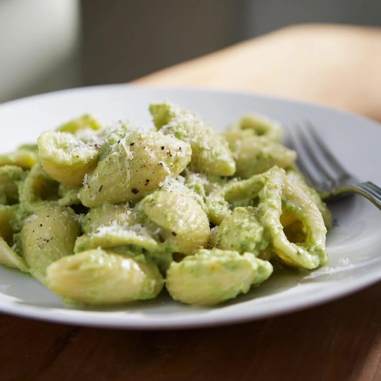 Close-up view of Creamy Avocado Pesto Mac, showing rich, creamy texture with basil and parmesan garnish, ready to serve for dinner.