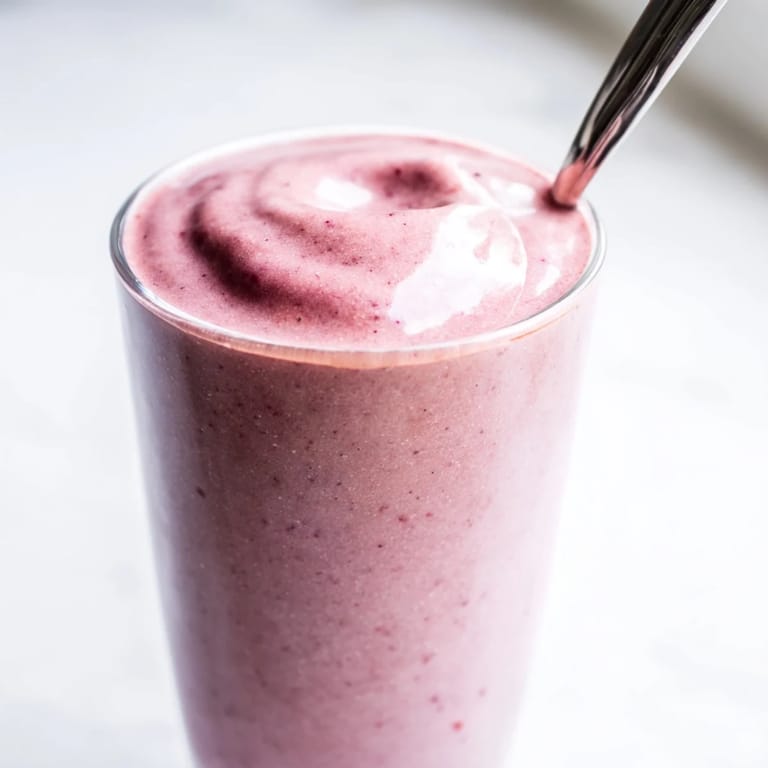 This Cherry Almond Smoothie shows a frothy, blended texture with banana and almond milk, perfect for a quick, healthy breakfast.  